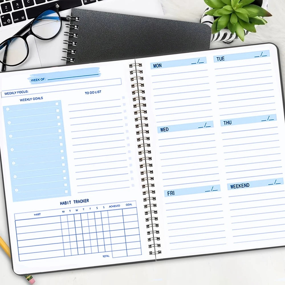 Open weekly planner of diary with pages to fill in on an office desk with a notepad and a keyboard.